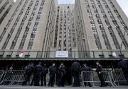 Uniformed officers stand in front of a multi-story building with metal fencing