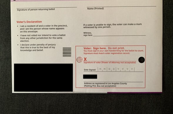 The back of an L.A. County return envelope There's a red box on the lower right corner with text reading "Voter: Sign here" and an X with a line. There's a small hole to the right of the line.