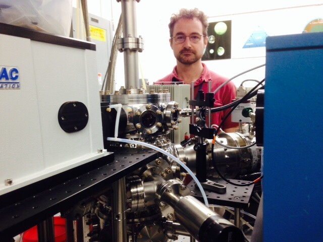 NASA researcher Kevin Hand stands next to a shiny metal machine used to create conditions similar to those on icy moons like Europa. He calls it "Europa in a can."