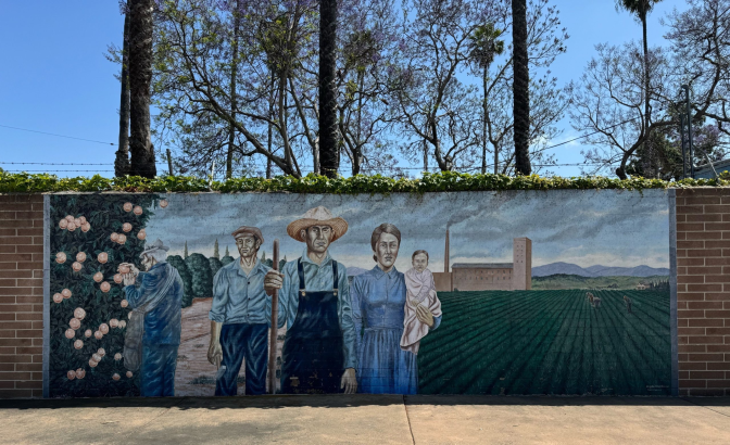 A mural features a farmer and his wife, but it also depicts a man working in an orange grove, a young man holding a hammer, and rows of crops in the background being tended by field workers.
