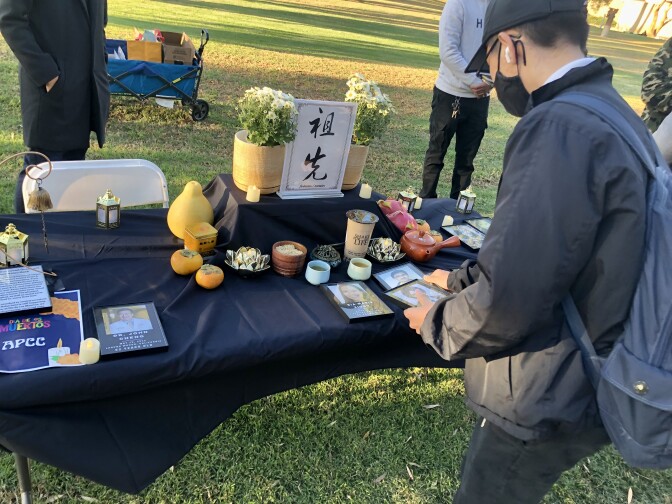 A man places photos of Asian people killed in hate incidents on a table covered in black.