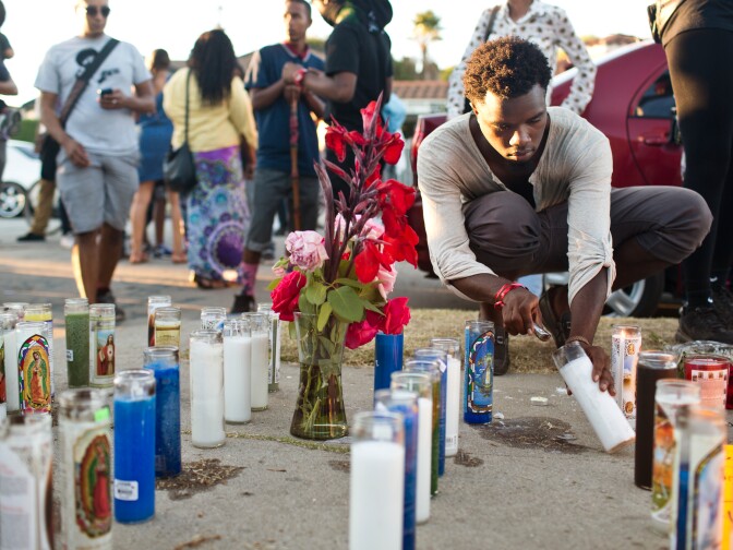 Malcolm McIntosh of Inglewood lights candles at a memorial where 25-year-old Ezell Ford who was fatally shot by Los Angeles police on Monday. McIntosh is hoping  for residents to organize soon and make a plan for how to prevent deputy-involved shootings.