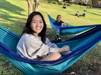 Two women sit in two separate hammocks next to each other on a grassy knoll at UCLA. 