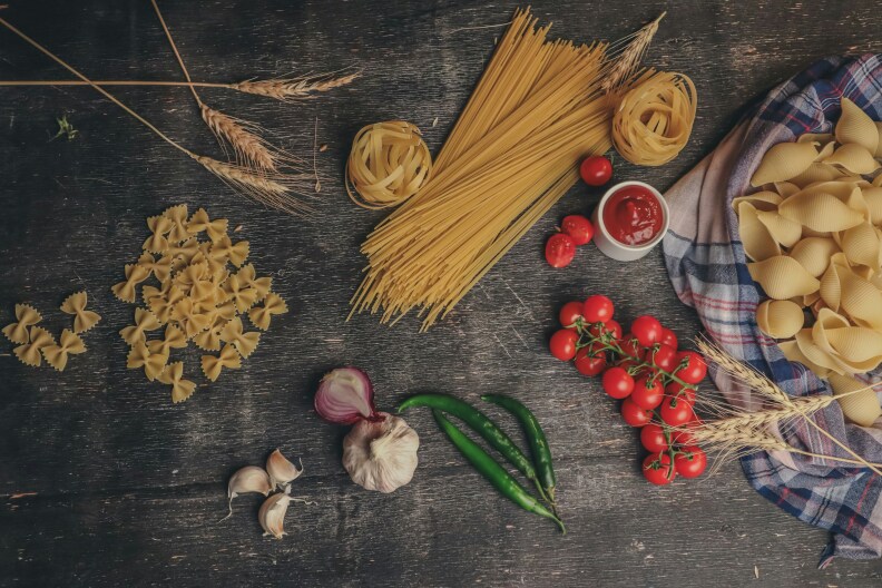 Pasta, fresh tomatoes, onions, garlic & pepper on table.