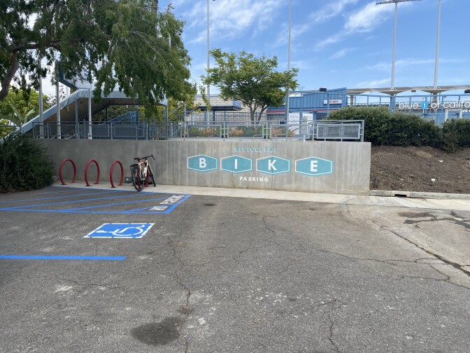 Red bike racks are seen against a concrete wall in a parking lot.