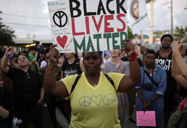 Desiree Griffiths, 31, of Miami, holds up a sign saying "Black Lives Matter", with the names of Michael Brown and Eric Garner, two black men recently killed by police, during a protest Friday, Dec. 5, 2014, in Miami. People are protesting nationwide against recent decisions not to prosecute white police officers involved in the killing of black men. (AP Photo/Lynne Sladky)