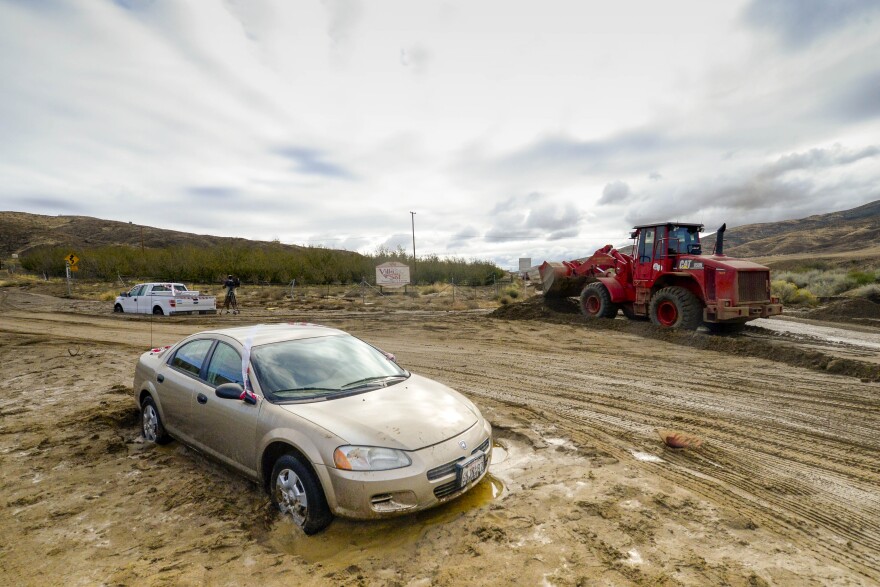 A Los Angeles County firefighter use a front-end loader to clear mud on Friday, Oct. 16, 2015, after a flash flood the day before sent mud and debris through Elizabeth Lake road in Leona Valley, Calif., trapping cars and closing roads. 