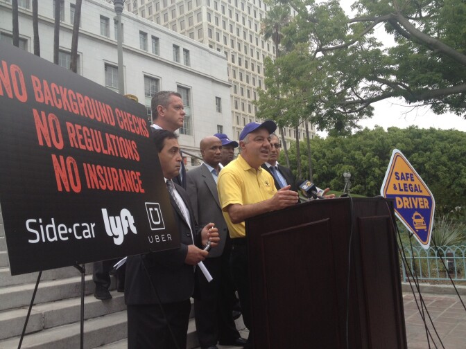 Los Angeles Yellow Cab driver Aydin Kavak, with representatives of other taxi companies, said ride-sharing services have stolen fares he's driven to pick up. 