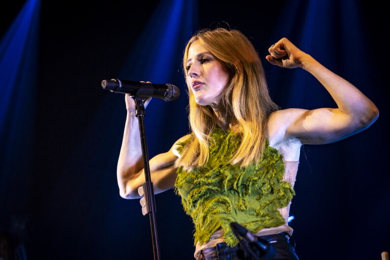 ellie goulding tour 2023 Ellie Goulding flexes her arms onstage while singing into a microphone.