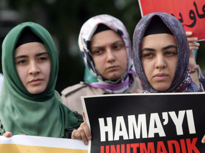 Members of a pro-Islamic human rights group and Syrians living in Turkey gather, one holding a placard that reads, "we did not forget Hama" as they stage a protest against the Syrian regime and its leader Bashar Assad during a protest outside the Syrian embassy in Ankara, Turkey, Monday, Aug. 1, 2011.