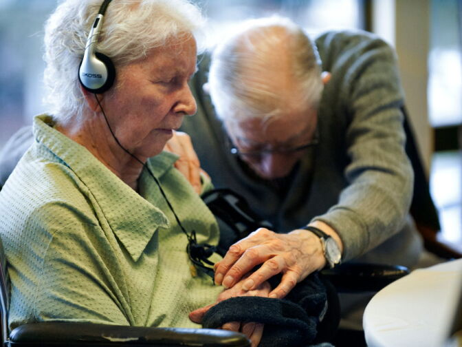 Frank M., 94, reaches for the hand of his wife of 68 years, Delores, 86, a resident with non-responsive dementia. While listening to music, Jessica Litchfield believes even the non-responsive patients have a "light in their eyes."