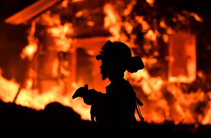 TOPSHOT - An inmate firefighter monitors flames as a house burns in the Napa wine region in California on October 9, 2017, as multiple wind-driven fires continue to whip through the region.  / AFP PHOTO / JOSH EDELSON        (Photo credit should read JOSH EDELSON/AFP/Getty Images)