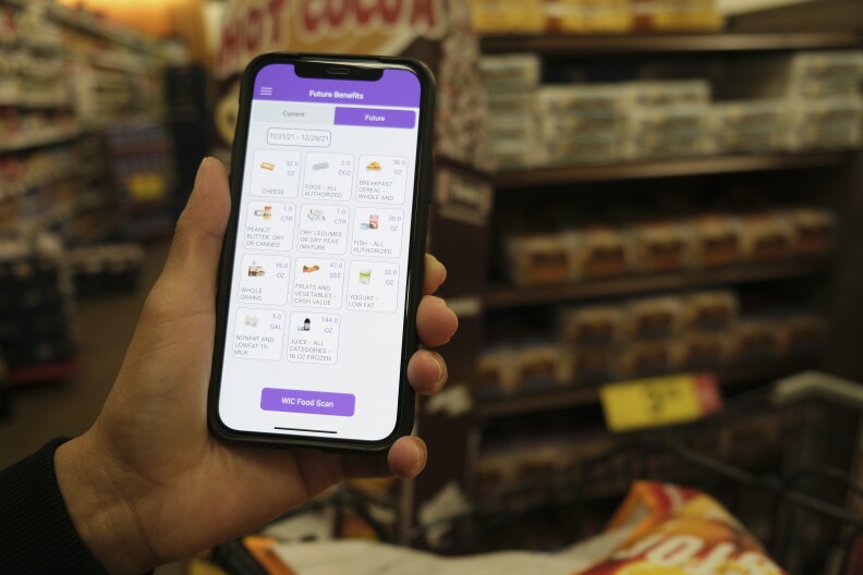 A person holding a mobile phone that displayes a list of "future benefits." at the bottom is a purple button with text reading "WIC Food Scan."