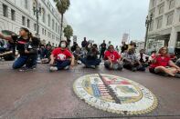 People sir cross-legged in the street holding protest signs
