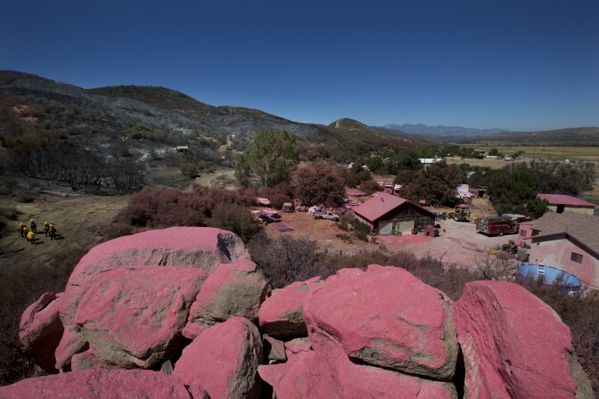 The San Bernardino National Forest team works on the Pilot Fire behind Ryan Nuckols’s home in Hesperia California on August 9th, 2016. The pink fire retardant line is one of the reasons why fire crews were able to save Nuckols’ house from the fire. 