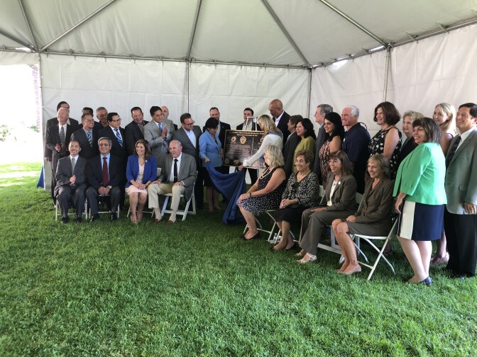 Officials pose as they unveil a commemorative plaque for the new trench.