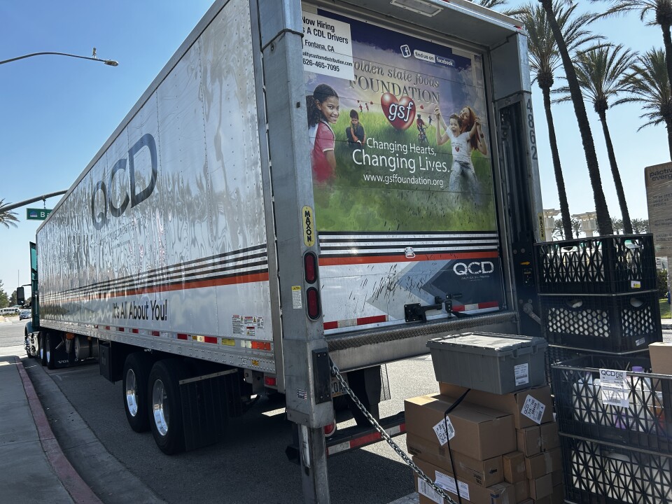 An image of the back of a large semi truck with boxes stacked on the liftgate. 