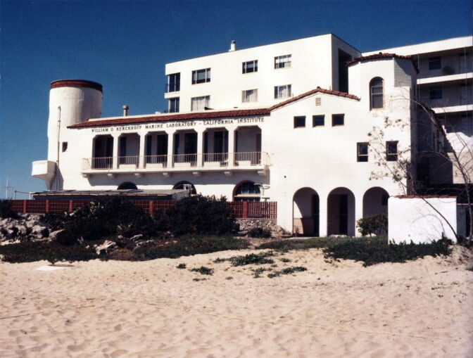 A photo shows a white marine lab building. The structure features a large tower and red-tiled roof