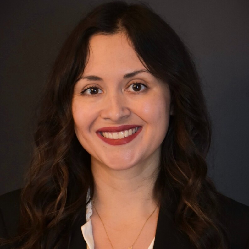 Marisa Alcaraz smiles at the camera. She has a light complexion, long dark hair and dark eyes.