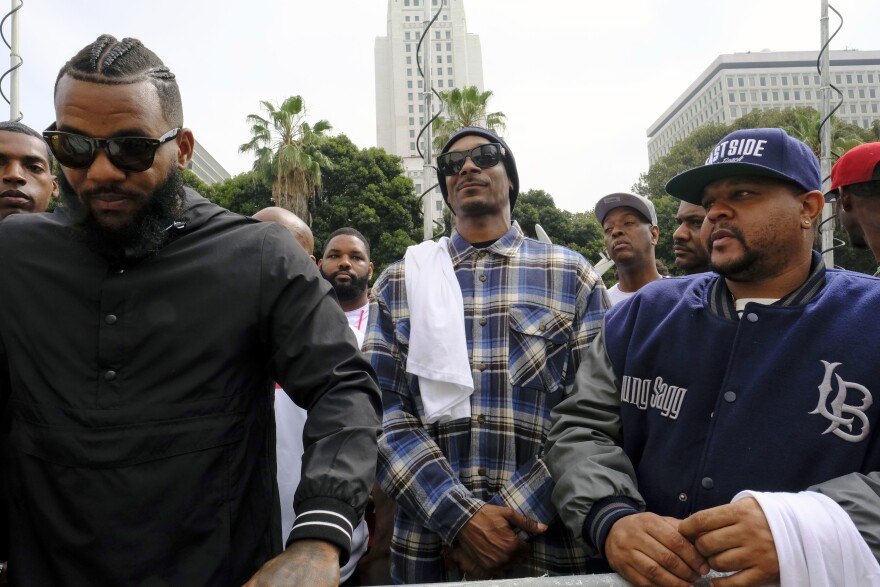 Rappers The Game, left, and Snoop Dogg, center, appear at a peaceful unification march outside of the graduation ceremony for the latest class of Los Angeles Police recruits in Los Angeles, Friday, July 8, 2016. Snoop shook hands with police officials and told reporters he hoped his presence would help reintroduce the black community to the Police Department and open a dialogue. The gathering comes a day after the shooting deaths of multiple police officers in Dallas on Thursday night.