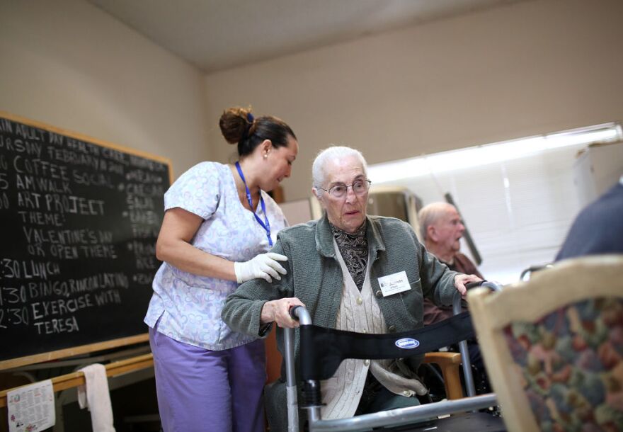 Program assistant Mayra Dittman (L) helps Juanita Gilbert get up to walk at the Lifelong Medical Marin Adult Day Health Care Center on February 10, 2011 in Novato, California.  LifeLong Medical Care in Novato is a state-licensed center that provides adult day health care and activities to nearly 60 Marin County seniors and would be forced to close if California Gov. Jerry Brown's proposed budget cuts were to be approved by the state legislature in order to make up for California's $28 billion deficit. The deep cuts to Medi-Cal would jeopardize up to 300 adult day care centers throughout California and displace nearly 37,000 people that depend on the service. 