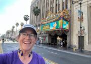 A woman smiling at the camera taken in front of an ornate movie theater.