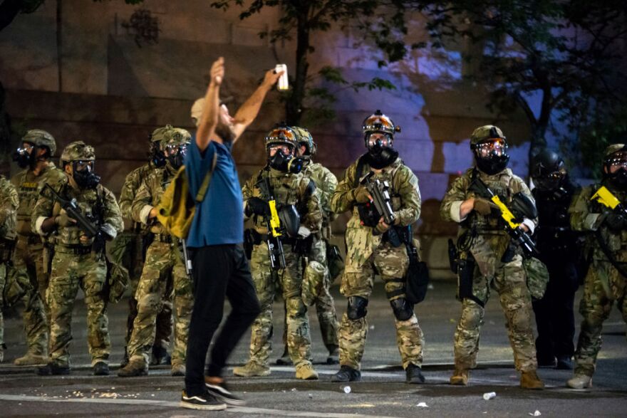 PORTLAND, OR - JULY 21: A protester holds his hands in the air while walking past a group of federal officers during a protest in front of the Mark O. Hatfield U.S. Courthouse on July 21, 2020 in Portland, Ore. The federal police response to the ongoing protests against racial inequality has been criticized by city and state elected officials. (Photo by Nathan Howard/Getty Images)