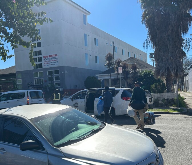 People loading luggage into a white fan on a residential street
