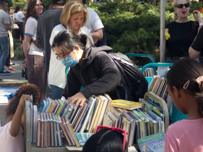 a woman looks at used books on a cart
