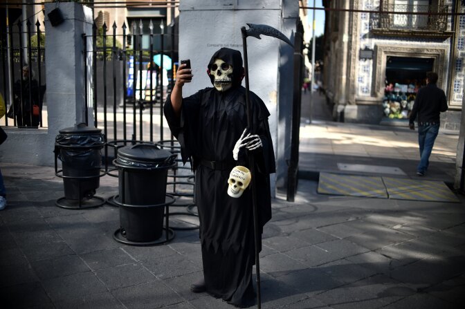 Death may not take a holiday but it does take a selfie. A man is dressed up for an exhibition of altars organized by the Historic Centre Foundation for Day of the Dead in Mexico City on November 1, 2016.