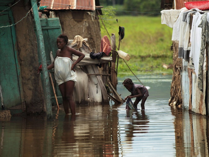 People stand outside homes in Petite Riviere, Haiti, that were flooded by Hurricane Tomas. Experts fear that cholera, a waterborne disease, could spread in crowded areas. Cholera has been confirmed in half of Haiti's 10 provinces.