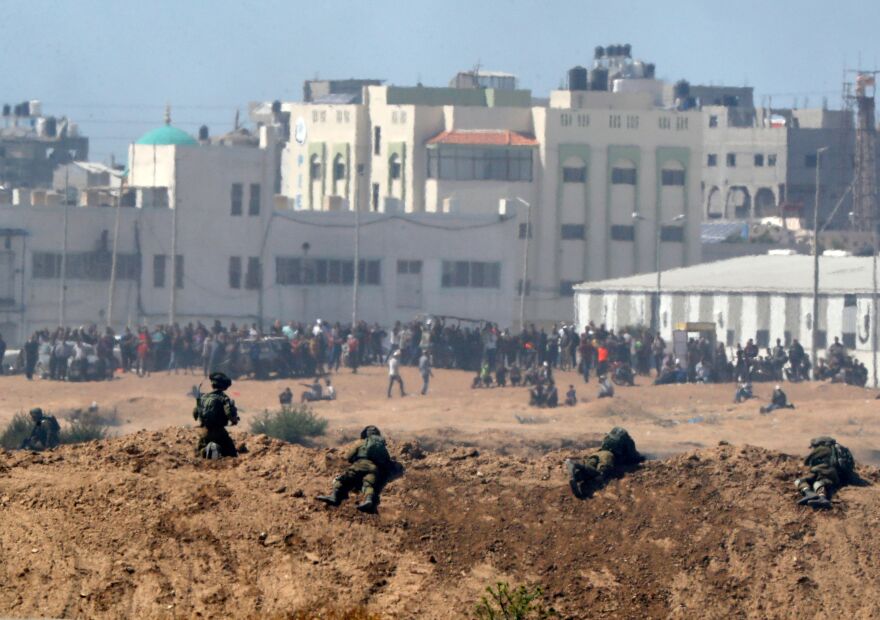 A picture taken on May 14, 2018 from the southern Israeli kibbutz of Nahal Oz across the border with the Gaza Strip shows Israeli soldiers keeping position and Palestinian protestors gathering along the border fence with Israel. - Dozens of Palestinians were killed by Israeli fire on May 14 as tens of thousands protested and clashes erupted along the Gaza border against the US transfer of its embassy to Jerusalem, after months of global outcry, Palestinian anger and exuberant praise from Israelis over President Donald Trump's decision tossing aside decades of precedent. (Photo by JACK GUEZ / AFP)        (Photo credit should read JACK GUEZ/AFP/Getty Images)