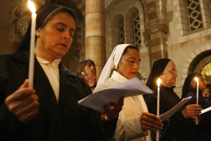 Dominican nuns light candles and read from pamphlets as they celebrate a mass.