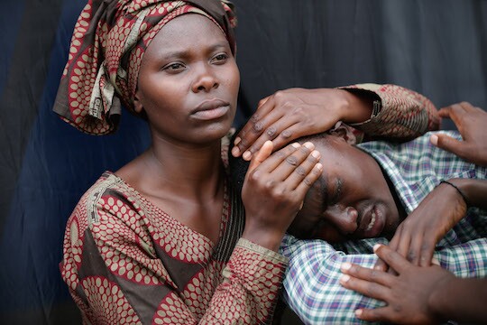 A woman consoles Bizimana Emmanuel, 22, during the 20th anniversary commemoration of the 1994 genocide at Amahoro Stadium April 7, 2014 in Kigali, Rwanda. Thousands of Rwandans and global leaders, past and present, joined together at the stadium to remember the country's 1994 genocide, when more than 800,000 ethnic Tutsi and moderate Hutus were slaughtered over a 100 day period.
