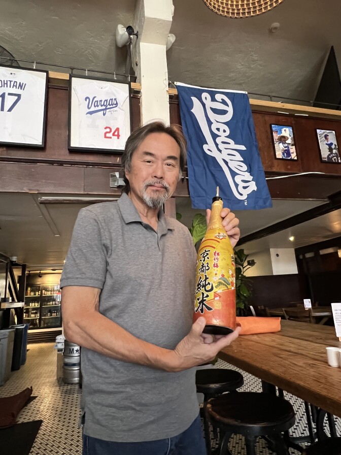 Don Tahara holds a bottle of the iconic 1.8 Liter Golden and orange bottle he pours Shohei Ohtani Sake shots with everytime Ohtani hits a home run.