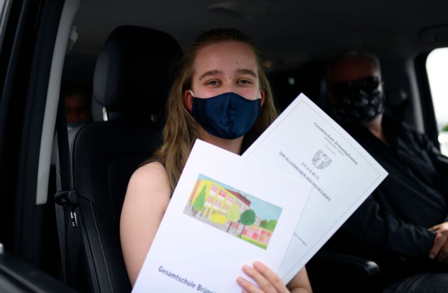 A high school graduate presents her baccalaureate certificate in her car during the ceremony of awarding of the Gesamtschule Bruenninghausen school at a drive-in cinema in Dortmund, western Germany, on June 18, 2020 during the coronavirus COVID-19 pandemic. - Because of the distance rules the comprehensive school presents the Abitur certificates at the drive-in cinema Dortmund at the former blast furnace Phoenix West. (Photo by Ina FASSBENDER / AFP) (Photo by INA FASSBENDER/AFP via Getty Images)