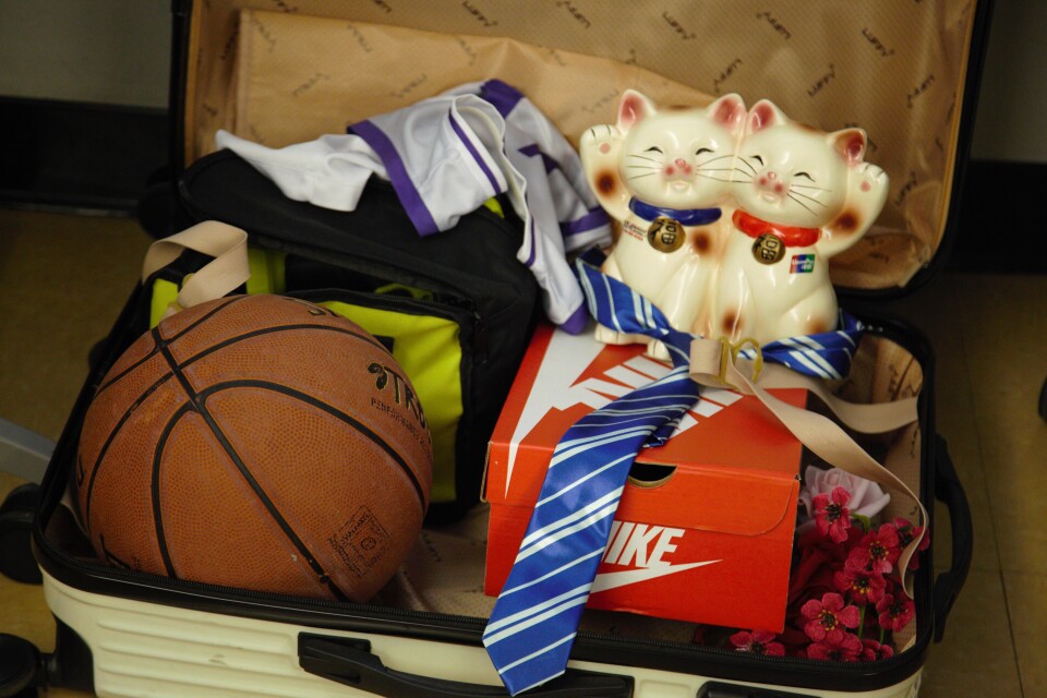 A suitcase is loaded with personal items, including a cat figurine, a basketball, and a Nike shoebox.