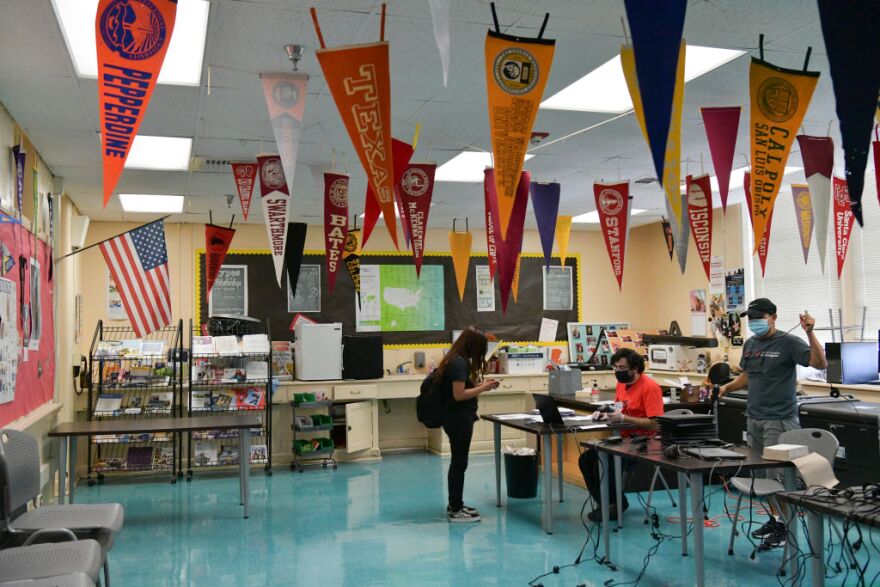 HOLLYWOOD, CALIFORNIA - AUGUST 13: IT Support Technician  Michael Hakopian (R) distributes computer devices to students at Hollywood High School on August 13, 2020 in Hollywood, California. With over 734,000 enrolled students, the Los Angeles Unified School District is the largest public school system in California and the 2nd largest public school district in the United States. With the advent of COVID-19, blended learning, or combined online and classroom learning, will become the norm for the coming school year. (Photo by Rodin Eckenroth/Getty Images)