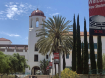 A white building with a bell tower and a dome alongside other buildings on a university campus 