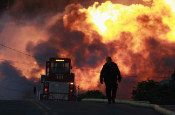 A law enforcement official runs towards a massive fire in a residential neighborhood September 9, 2010 in San Bruno, California. 