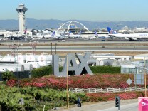 A traveler pulls his bags while walking past an LAX sign at Los Angeles International Airport as access roads were closed with flights delayed and cancelled after a gunman reportedly shot 3 people at a security checkpoint on November 1, 2013 in Los angeles, California. 