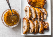 a bowl of sauce next to a plate of cooked turkey thigh