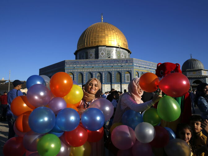 TOPSHOT - A Palestinian woman holds balloons as Muslims gather for the morning Eid al-Fitr prayer near the Dome of Rock at the Al-Aqsa Mosque compound, Islam's third most holy site, in the Old City of Jerusalem on June 25, 2017.
Muslims worldwide celebrate Eid al-Fitr marking the end of the fasting month of Ramadan. / AFP PHOTO / AHMAD GHARABLI        (Photo credit should read AHMAD GHARABLI/AFP/Getty Images)