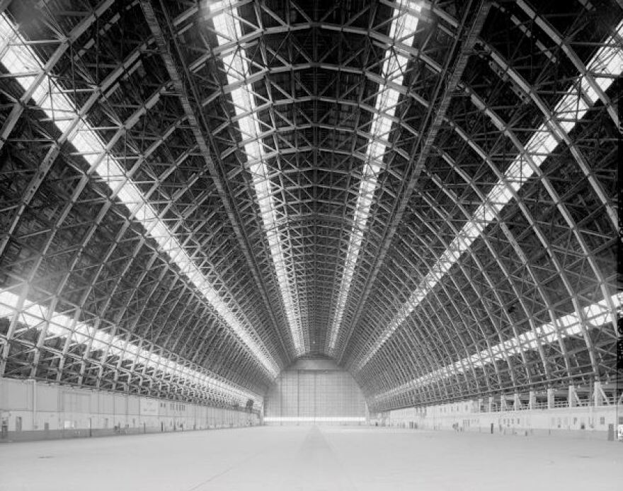 A black and white photograph of a half egg shaped building with visible scaffolding.