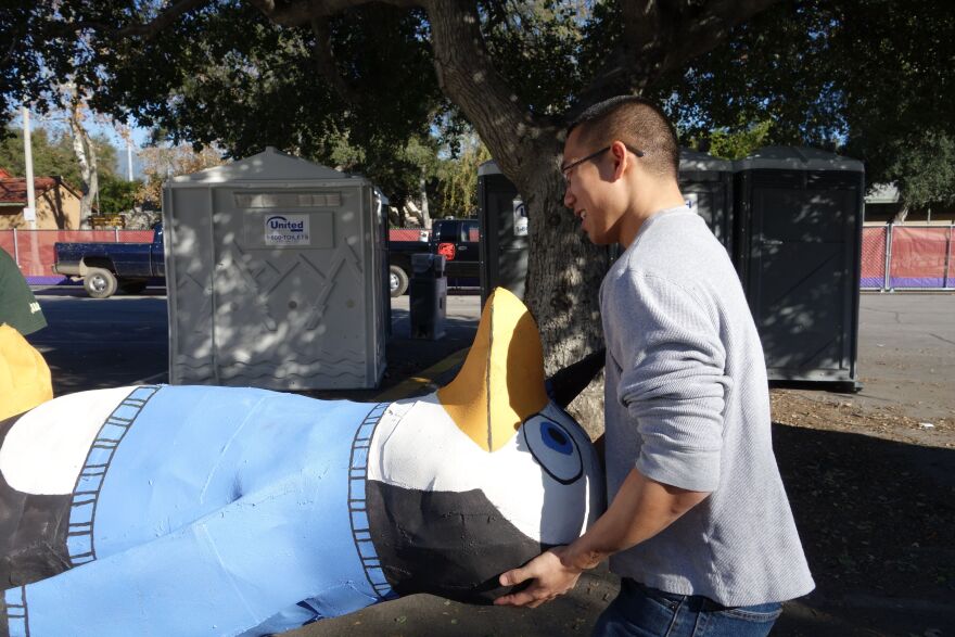 Cal Poly Pomona student Nelson Chang unloads one of a dozen steel and foam penguin sculptures that will be covered with California-grown flowers and displayed on the university's Rose Parade float.