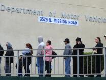File: People wait in line outside of the State of California Department of Motor Vehicles (DMV) in Los Angeles, California on February 13, 2009.   