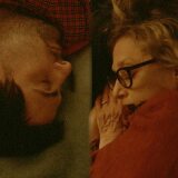 Two people sleep across from each other on a couch 