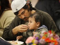 LOS ANGELES, CA - APRIL 10: A man and child receive a hot meal during the annual Good Friday Easter event at the Los Angeles Mission on Good Friday, April 10, 2009 in Los Angeles, California. Nurses and Volunteers provided Easter baskets and toys to homeless children, including some 3,000 hot meals, 2,000 pairs of shoes and podiatric care for the homeless of Central City East in Los Angeles. Also known as Skid Row, Central City East is home to several thousand homeless people, one of the largest homeless populations in the nation. (Photo by David McNew/Getty Images)