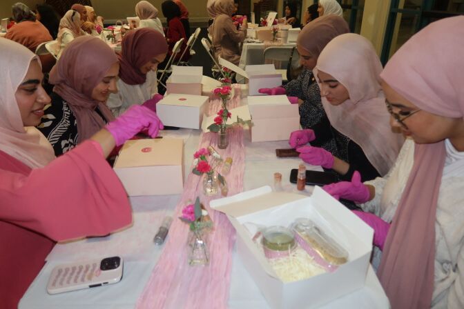 Women wearing shades of pink and pink gloves make chocolate. 