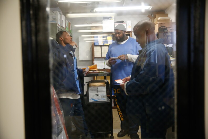 A group of incarcerated folks go over notes in an office.
